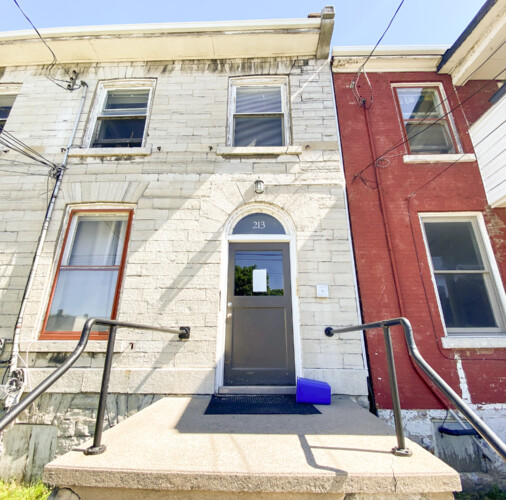A limestone facade and arched entrance mark the front of 213 Queen Street in downtown Kingston. Limestone facade with arched front door and railings at 213 Queen Street, Kingston, Ontario